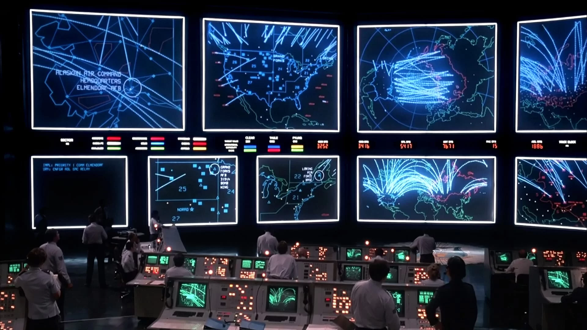 Scene from the movie WarGames showing humans interacting with multiple computer screens, illustrating how information systems serve as human-driven interfaces for problem solving
